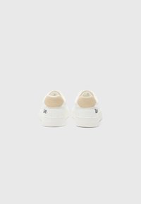 White sneakers with a smooth leather upper, beige suede accents on the heel, textured rubber sole, and embroidered logo on the side.