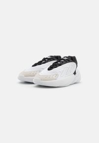 Zapatillas blancas y negras con una mezcla de cuero y gamuza. Presentan acentos texturizados, una punta redondeada y cordones en contraste.