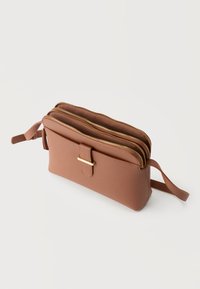 Καφέ τσάντα ώμου από υφή δέρματος με δύο ανοιχτές θήκες με φερμουάρ και μια μπροστινή τσέπη με ιμάντα και λεπτομέρεια με χρυσή αγκράφα.