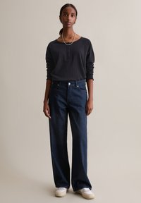 Ciemnoniebieskie dżinsy o szerokich nogawkach wykonane z denimu, zestawione z długim rękawem w kolorze grafitowym, z dekoltem zapinanym na guziki i luźnym krojem.