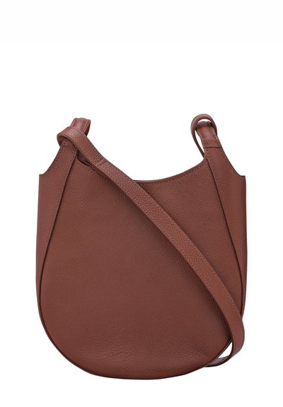 Brown leather handbag with a curved shape, textured surface, and a long adjustable strap. Features minimalistic design and streamlined accents.