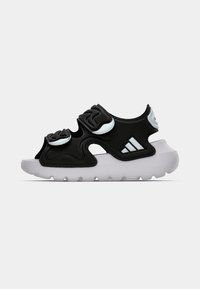 Μαύρα αθλητικά παπούτσια με υφή στην επάνω επιφάνεια και ξεχωριστές καμπυλωτές λεπτομέρειες, λευκή φιλόδοξη σόλα και λογότυπο της μάρκας στο πλάι. Ελαφρύς σχεδιασμός.