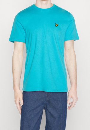 Turkusowy bawełniany t-shirt z okrągłym dekoltem i krótkimi rękawami, z małym żółtym logo na lewej piersi. Prosty, casualowy design.