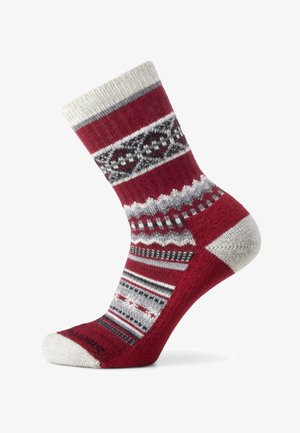 Punainen villasukka, jossa on valkoisia, harmaita ja mustia pohjoismaisia kuvioita. Sukassa on resorireunus sekä vahvistetut varvas- ja kantapääosat.