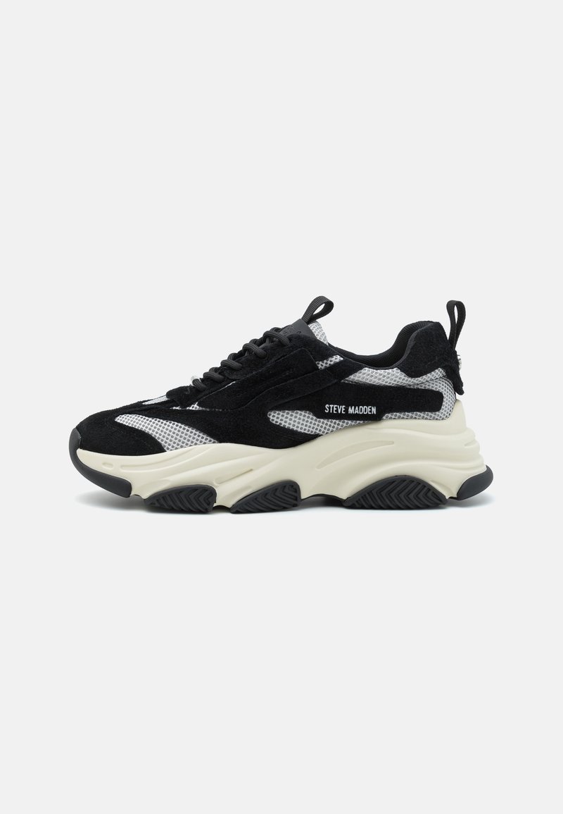 Fekete és szürke sneaker, amely hálós és velúr anyagok kombinációjából készült. Vastag, fehér középtalppal, texturált fekete talppal és húzófüllel rendelkezik.