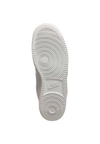 Semelle de sneaker blanche présentant des motifs circulaires concentriques, une texture antidérapante et un logo de marque visible au centre.