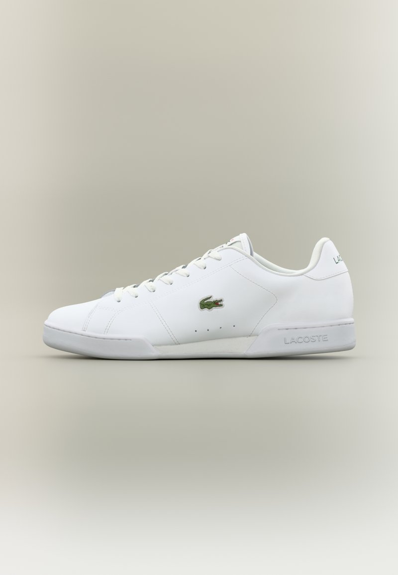 Fehér bőr sportcipők lekerekített orral, fűzős kialakítással, zöld krokodil logóval, valamint szürke kiegészítőkkel a sarokon és a nyelvén.