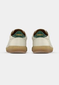 Ζευγάρι λευκών αθλητικών παπουτσιών με διαφανείς καφέ σόλες, πράσινες πίσω γλωττίδες και χρυσό λογότυπο "Blauer" σε λευκό απλό φόντο.