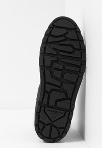 Černá gumová podrážka boty s texturovaným vzorem, která obsahuje geometrický vzor a vyražené jméno značky "VAGABOND" s velikostí "37".