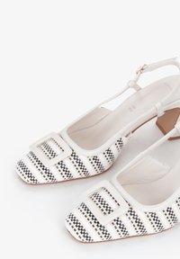 Scarpe bianche slingback con punta quadrata, dotate di una tomaia intrecciata a pattern in bianco e nero e un accento di fibbia quadrata a contrasto.