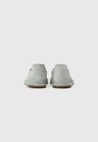 Light gray suede slip-on shoes with a soft texture, rounded edges, and a minimalistic design. Features simple stitching and a rubber sole.