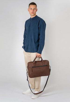 Brown leather briefcase with top handles and a detachable shoulder strap, featuring a front zippered pocket and a smooth texture.