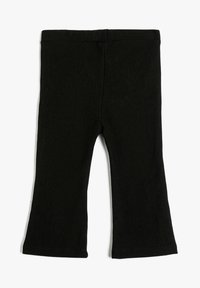 Pantalones para niño pequeños de tela de punto ribeteada negra con cinturilla elástica y ligero acampanado en el dobladillo, dispuestos en una superficie blanca.
