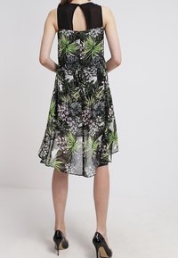 Bezramenné šaty s černým vrškem a květinovou síťovanou sukní s zelenými a růžovými vzory. Plynulý design s detailem ve tvaru klíčové dírky vzadu.