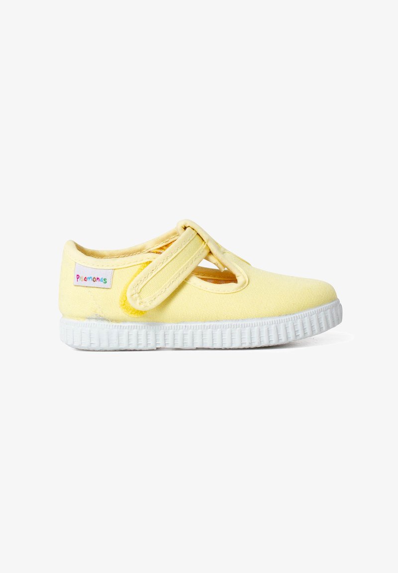 Zapato de algodón amarillo con una correa de Velcro, que presenta un diseño lateral con cortes, suela de goma blanca y agarre texturizado para tracción.