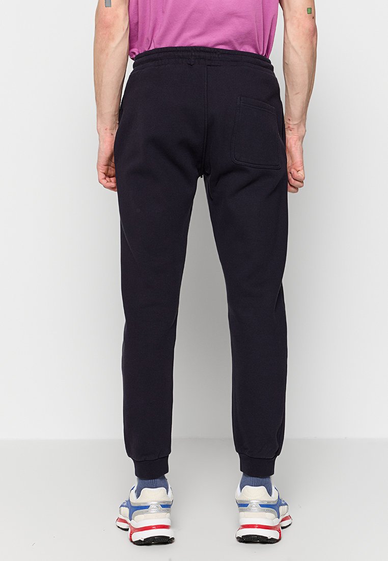Pantaloni jogger blu navy realizzati in tessuto misto cotone, con gambe affusolate, vita elastica e dettagli sulla tasca posteriore. Abbinati a sneaker.