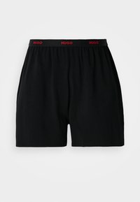 Sorte bomullsboxershorts med elastisk midjebånd med rødt "HUGO" merke. Enkel design uten mønstre eller tilleggselementer.