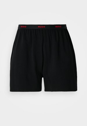 Black cotton boxer shorts featuring an elastic waistband with red "HUGO" branding. Simple design with no patterns or additional accents.