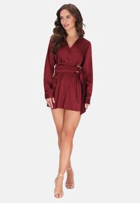 Burgundská zavinovací šaty s dlouhými rukávy, páskem v pase a plisovanou sukní. Vyrobené z hladkého materiálu, mají hluboký výstřih do V a stylový střih.