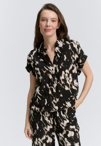 Camicia a maniche corte nera e beige con motivo, colletto, bottoni frontali e vestibilità rilassata, abbinata a pantaloni a motivi coordinati.
