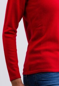Roter Pullover mit langen Ärmeln aus Strick mit weicher Textur. Verfügt über ein körpernahes Design, Rippbündchen und einen leicht abgerundeten Saum.