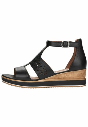 Sort læder kilehæl sandal med ankelrem og spænde, udskårede blomsterdetaljer på siden og tanfarvet tekstureret kilehæl med sort sålekant.