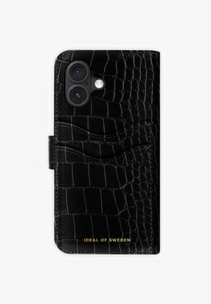 Černý telefonní obal s reliéfem krokodýlí kůže, texturovaným povrchem, bočním slotem na kartu a zlatým logem ve spodní části. Bezpečně se zavírá pomocí klapky.