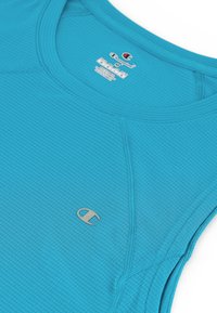 Niebieskozielony sportowy top bez rękawów wykonany z teksturowanej tkaniny, z okrągłym dekoltem i małym haftowanym logo w dolnym lewym rogu.