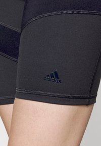 Černé sportovní šortky Adidas s hladkým, pružným povrchem. Mají přiléhavý střih, ploché švy a decentní logo.