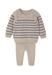 Beige Strickpullover mit marineblauen Streifen und Schulterdetail mit vier Knöpfen, kombiniert mit passenden beige Strickhosen, die beide gerippte Bündchen aufweisen.
