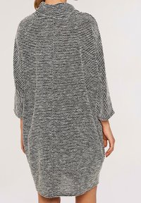 Robe oversize en maille noire et blanche, dotée d'un col montant, de manches trois-quarts et d'un motif à rayures horizontales texturées.