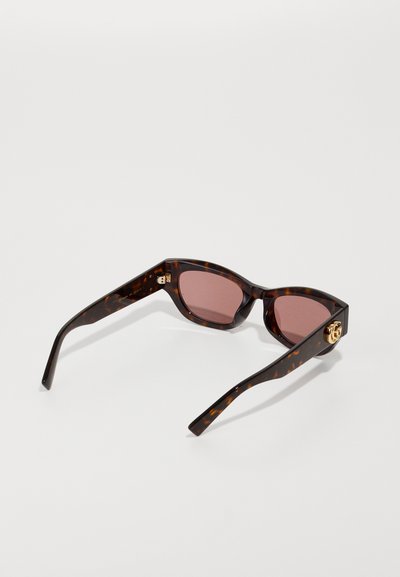 Lunettes de soleil en écaille de tortue avec des montures angulaires, des verres roses et des accents en métal doré sur les branches. Fini brillant et design élégant.
