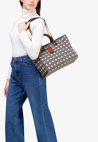 Borsa a tote con motivo beige realizzata in tessuto, con accenti neri e hardware dorato. Presenta un'etichetta in pelle removibile e una tracolla a catena.