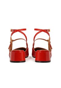 Red patent leather block-heeled sandals with cross-strap design and adjustable ankle buckle. Smooth texture and open back.