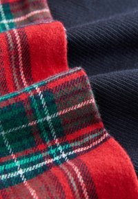 Wollstoff mit roten und grünen Karomustern sowie einfarbigen navy Abschnitten. Strukturiertes Finish mit weichem, warmem Aussehen.