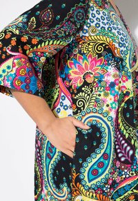 Vestido colorido con estampado de paisley y mangas acampanadas, que presenta vibrantes diseños florales en rosa, azul y verde sobre un fondo negro, incluye bolsillos.