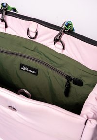 Intérieur d'un sac à main rose avec une doublure vert olive, comportant une poche zippée et un matériel noir. Une bandoulière colorée est attachée en haut.