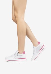 Sneaker bianche con dettagli rosa, pannelli in rete e chiusura con zip. Presentano una suola bianca spessa con una striscia rosa.