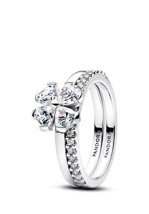 Silberner Pandora-Ring mit einem blumenförmigen Cluster aus vier herzförmig geschliffenen klaren Steinen und kleineren Steinen entlang des Rings.