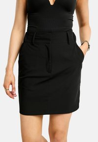 Fekete szoknya, testhez simuló kialakítással, két oldalzsebbel és sima tapintású anyaggal. Középcombig érő hosszúságban, tiszta szegéllyel.