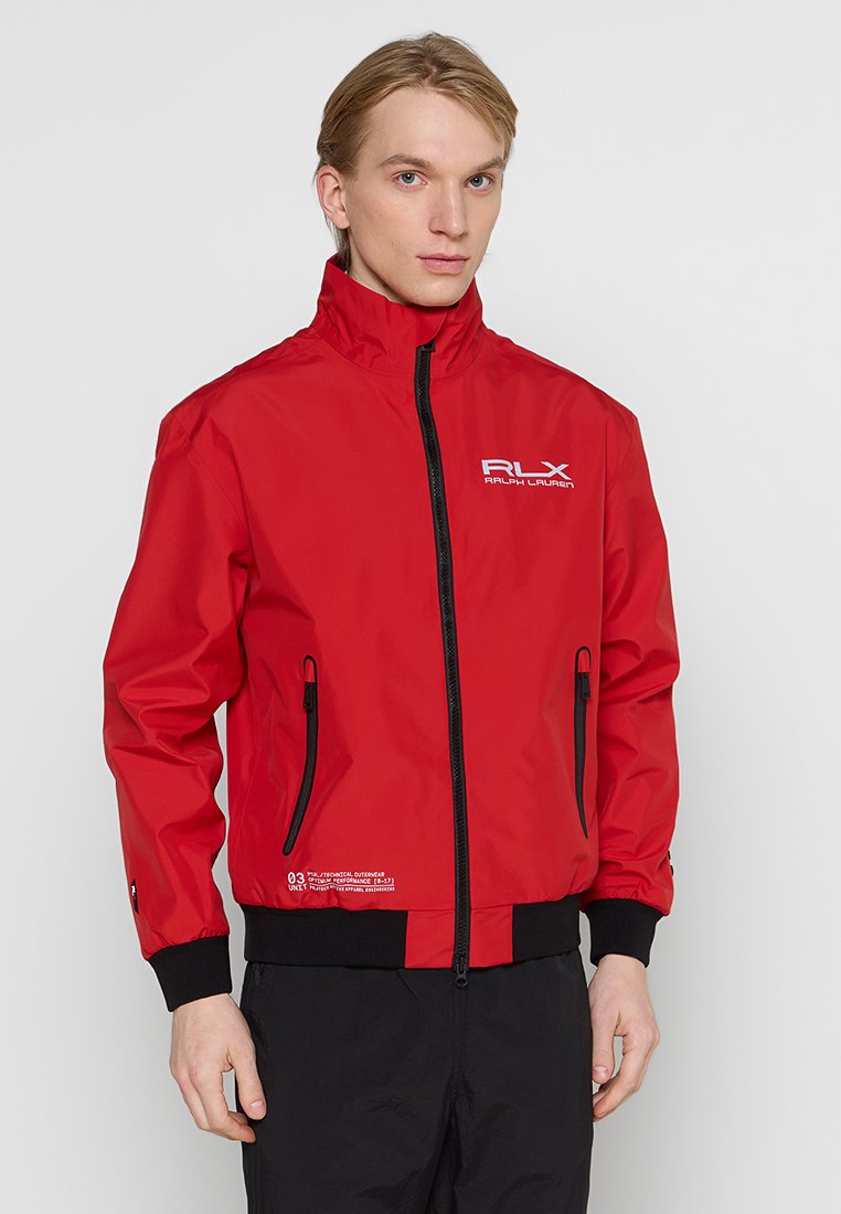 La chaqueta roja RLX de Ralph Lauren cuenta con un collar alto, cremallera negra y bolsillos laterales. Está hecha de un material suave y ligero.