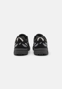 Schwarze Sportschuhe mit grauen Akzenten, ausgestattet mit einem strukturierten Mesh-Obermaterial, gepolstertem Fußbett und ausgeprägtem Profil für besseren Halt.