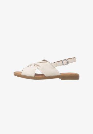 Beige flache Sandale für Damen mit verknoteten Frontriemen, verstellbarer Schnalle hinten und brauner Sohle.