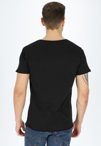 Black short-sleeve t-shirt in a cotton blend, featuring a round neckline and a seamless design. Worn with blue denim jeans.
