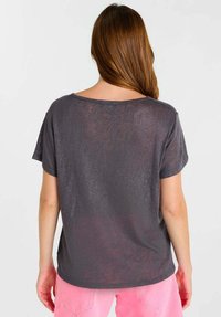 Grijs T-shirt met korte mouwen en een relaxte pasvorm, met een ronde halslijn en een subtiele glinsterende textuur. De gladde stof valt losjes.