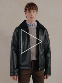 Mustast kunstnahast jakk karvase kraega, tõmblukuga taskute ja soonikkoes varrukakääridega, kihiliselt halli kampsuni ja särgi peal.