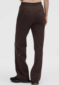 Braune Sporthose mit lockerer Passform, elastischem Bund, kontrastierenden Nähten und Logodetail am Saum. Glattes, strukturiertes Material.