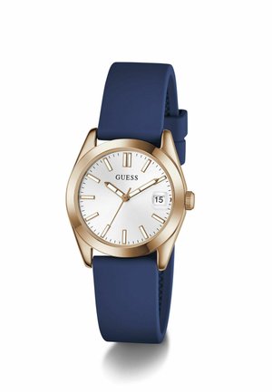 Ceas GUESS cu aspect auriu, cadran alb, marcaje aurii, fereastră pentru dată și curea din silicon albastru închis, afișând ora 10:10:37.