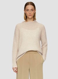Hellrosa gestrickter Pullover mit hohem Kragen, gerippter Textur und leicht oversized Passform, kombiniert mit beigen, weit geschnittenen Hosen.