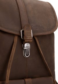 Sac à dos en cuir marron avec une boucle en métal argenté et un logo de marque embossé sur le rabat avant.